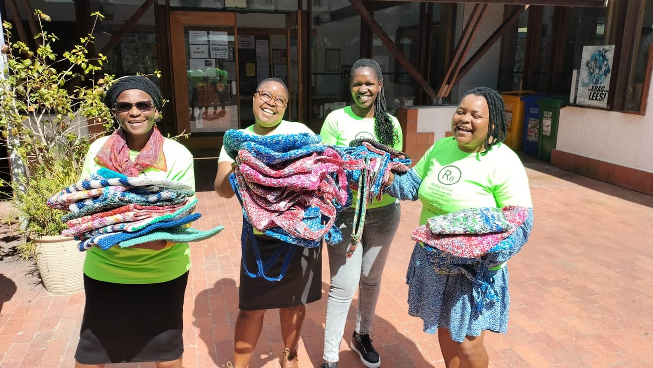 The Re.Bag.Re.Use team holding handcrafted crocheted products